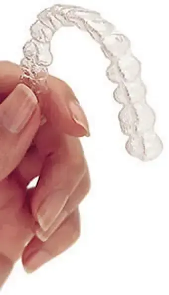 A clear aligner tray held in the hand